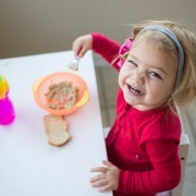Smiling young toddler eating breakfast