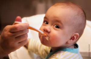 Young baby boy being fed with a spoon
